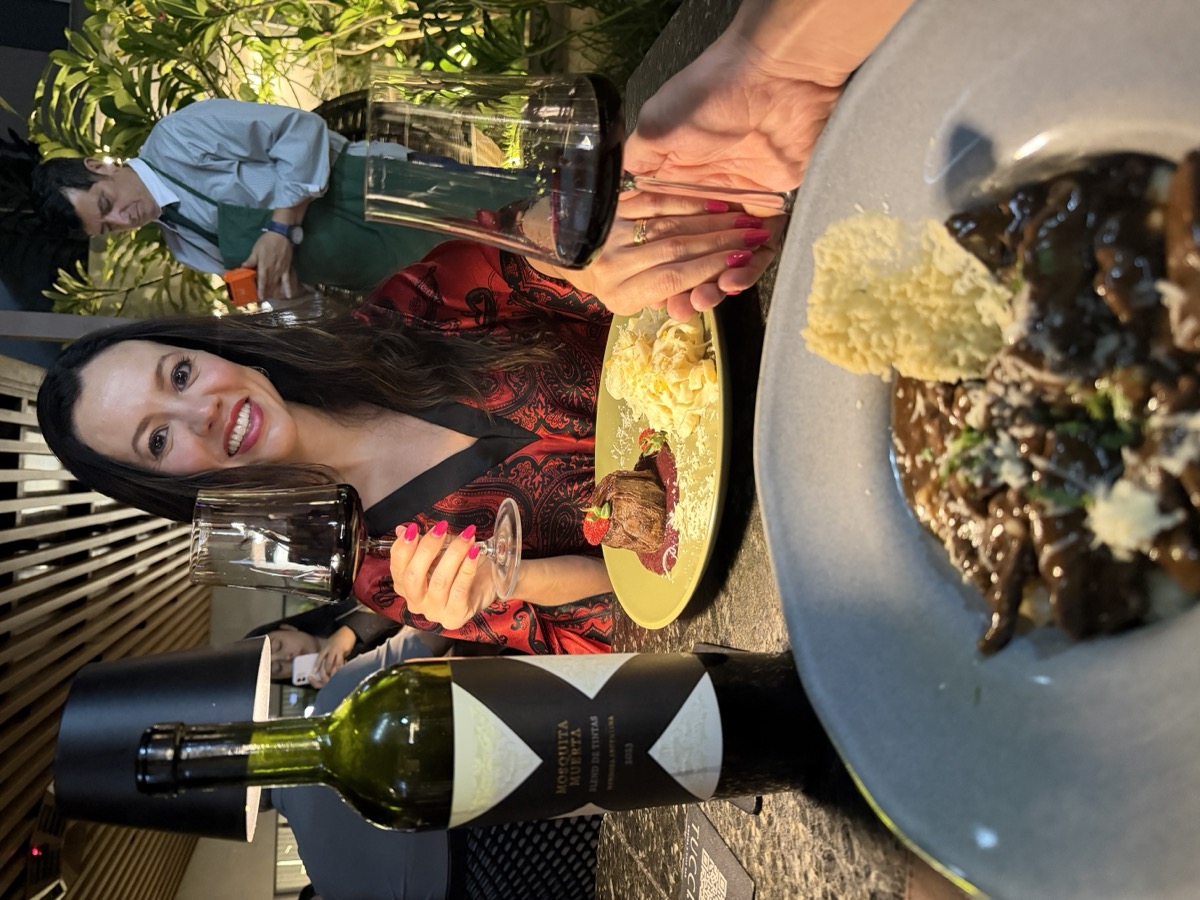 Dra. Paula Rosa brindando com uma taça de vinho